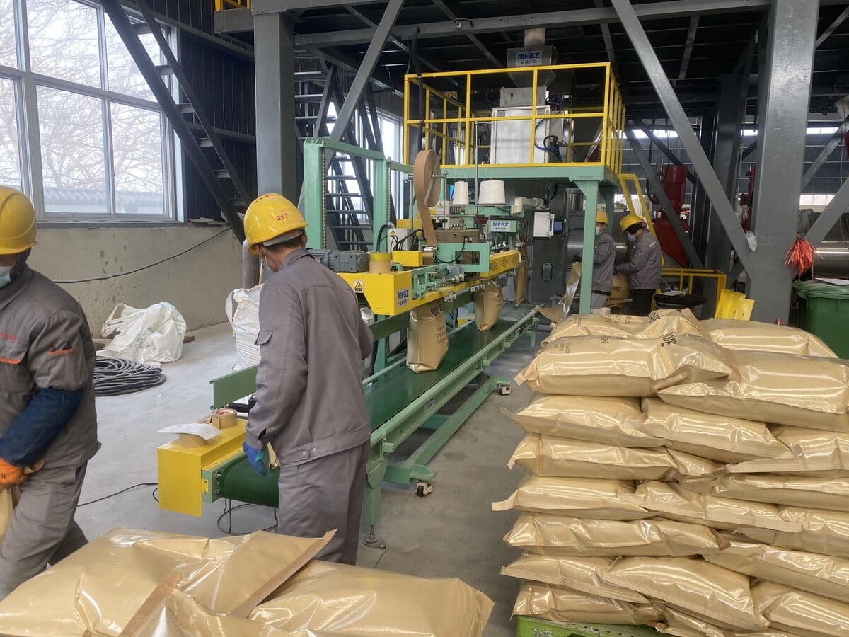 Workers operating automated PAM packaging line with bagging equipment