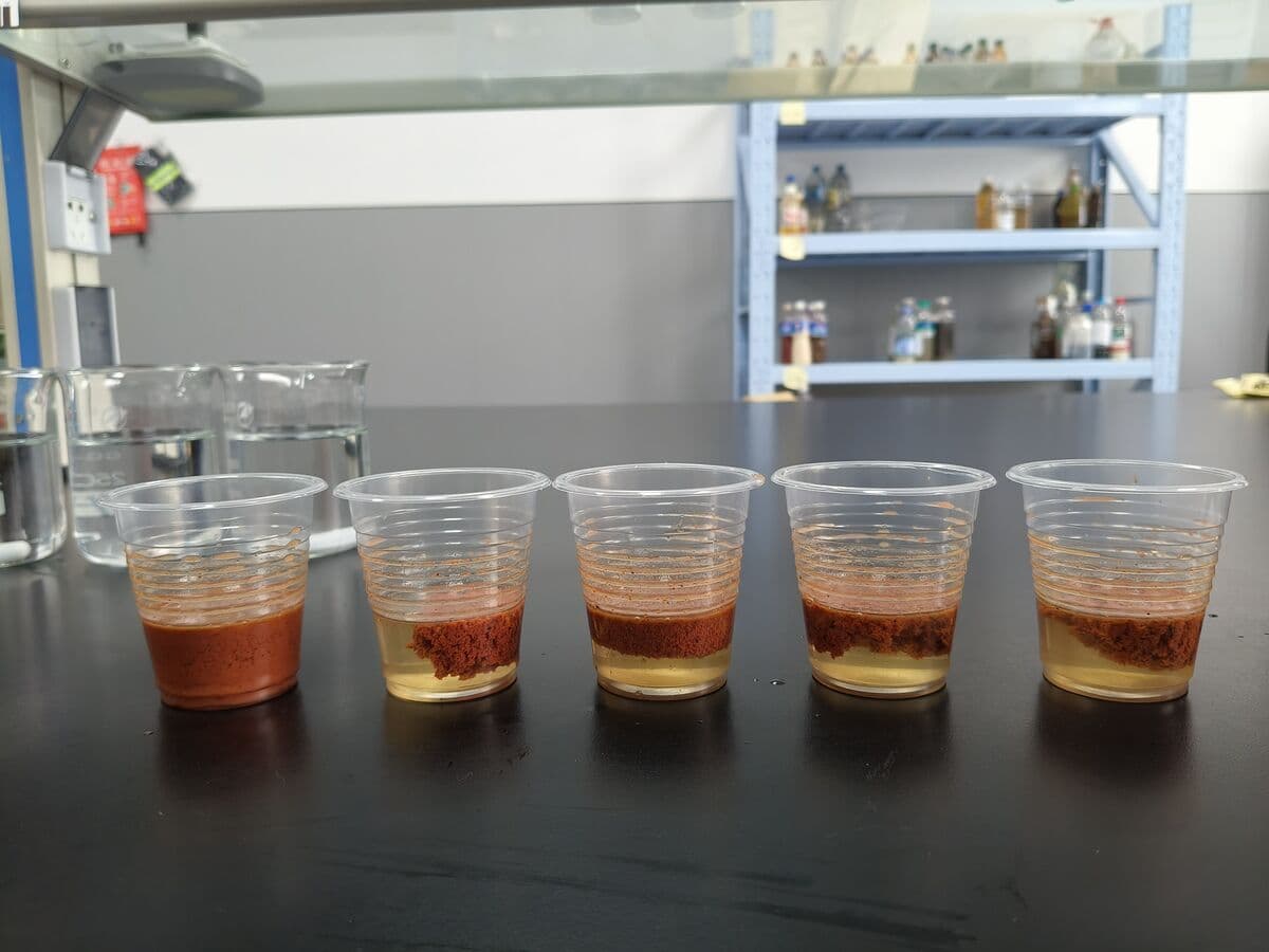 Graduated cylinder after polymer addition showing a clear supernatant forming above settled tailings solids